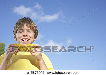Portrait of boy (7-9) eating corn on the cob View Large Photo Image Stock Image - Portrait of boy (7-9) eating corn on the cob. Fotosearch