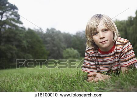 Stock Image - Portrait of boy (7-9) lying in meadow. Fotosearch