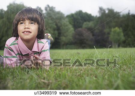 Stock Photo - Portrait of boy (7-9) lying in meadow. Fotosearch