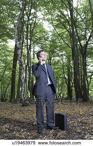 Portrait of business man in forest talking on mobile phone View Large Photo Image Stock Photo - Portrait of business man in forest talking on mobile phone. Fotosearch