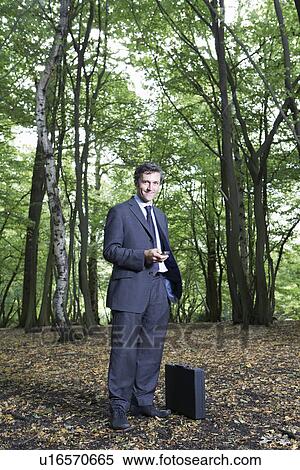 Portrait of business man in forest holding mobile phone smiling View Large Photo Image Stock Photography - Portrait of business man in forest holding mobile phone smiling. Fotosearch