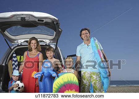 Stock Image - Portrait of family with three children (3-11) at beach by car. Fotosearch
