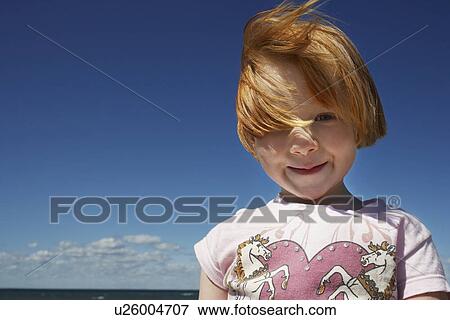 Stock Photo - Portrait of ginger haired girl (5-6) against blue sky. Fotosearch