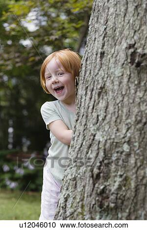 Portrait of girl (3-4) peeking from behind tree laughing View Large Photo Image Stock Image - Portrait of girl (3-4) peeking from behind tree laughing. Fotosearch