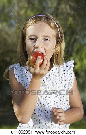 Portrait of girl (5-6) eating apple View Large Photo Image Stock Image - Portrait of girl (5-6) eating apple. Fotosearch