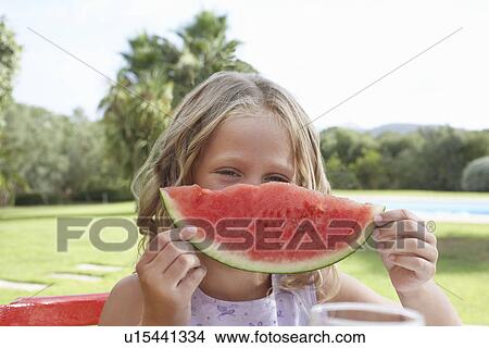 Picture - Portrait of girl (5-6) holding slice of watermelon. Fotosearch