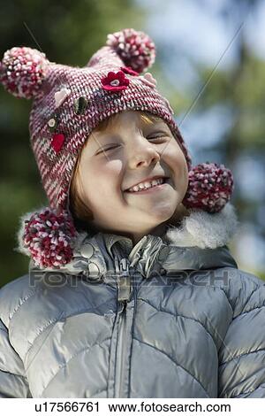 Stock Image - Portrait of girl (5-6) in winter clothes smiling. Fotosearch