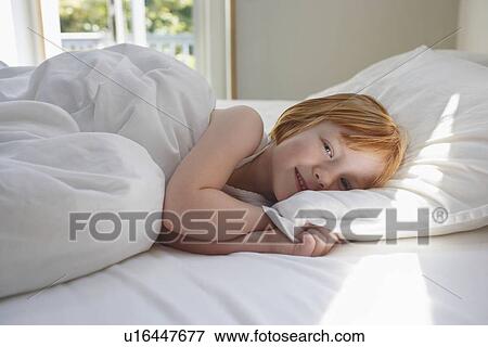 Portrait of girl (5-6) lying in bed smiling View Large Photo Image Stock Photo - Portrait of girl (5-6) lying in bed smiling. Fotosearch