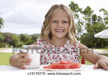Portrait of girl (5-6) sitting at table with watermelon and glass of milk View Large Photo Image Stock Image - Portrait of girl (5-6) sitting at table with watermelon and glass of milk. Fotosearch