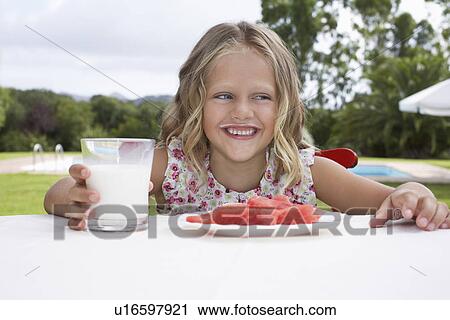 Portrait of girl (5-6) sitting at table with watermelon and glass of milk laughing View Large Photo Image Stock Image - Portrait of girl (5-6) sitting at table with watermelon and glass of milk laughing. Fotosearch