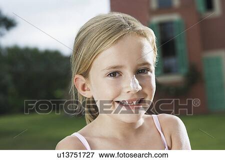 Stock Photo - Portrait of girl (5-6) with sunscreen on nose. Fotosearch