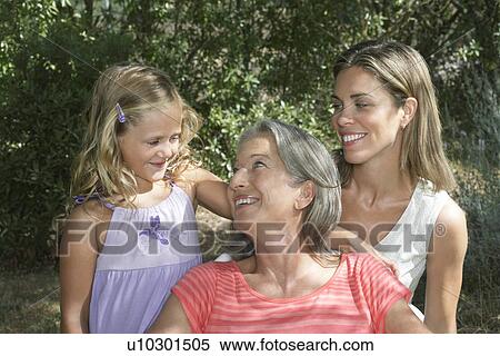 Stock Photography - Portrait of grandmother mother and daughter (5-6) in garden. Fotosearch