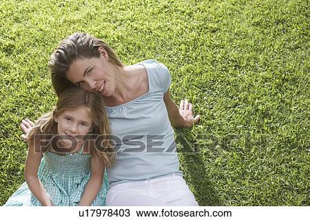 Stock Image - Portrait of mother and daughter (5-6) sitting on lawn. Fotosearch
