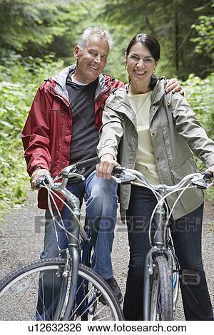 Portrait of senior man and middle-aged woman on bicycles in forest smiling View Large Photo Image Stock Photograph - Portrait of senior man and middle-aged woman on bicycles in forest smiling. Fotosearch