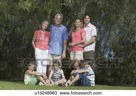 Stock Image - Portrait of three-generation family with three children (6-11) under tree. Fotosearch