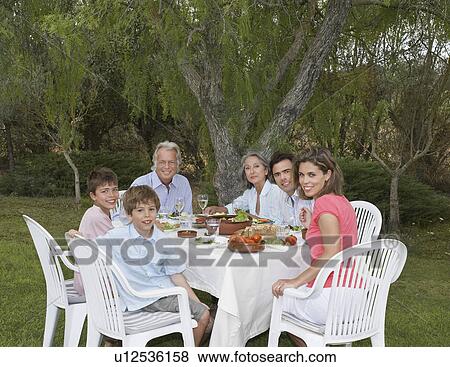 Portrait of three-generation family including children (6-11) at sitting garden table View Large Photo Image Stock Photo - Portrait of three-generation family including children (6-11) at sitting garden table. Fotosearch