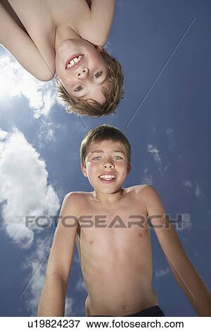 Stock Photo - Portrait of two boys (6-11) bending down view from below. Fotosearch