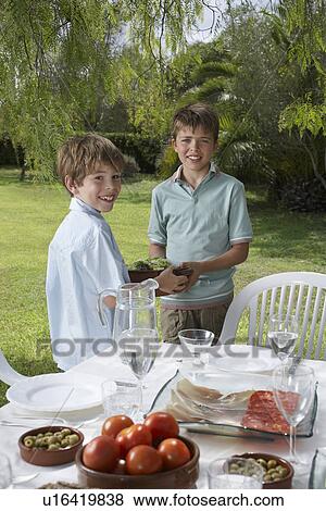 Stock Photo - Portrait of two boys (6-11) by table in garden. Fotosearch