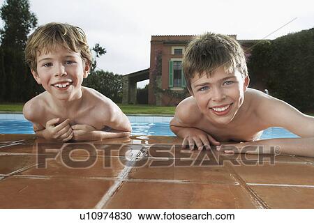 Stock Image - Portrait of two boys (6-11) leaning on edge of pool. Fotosearch