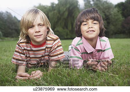 Portrait of two boys (7-9) lying in meadow View Large Photo Image Stock Photo - Portrait of two boys (7-9) lying in meadow. Fotosearch