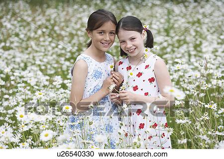 Stock Image - Portrait of two girls (7-9) in meadow full of flowers. Fotosearch