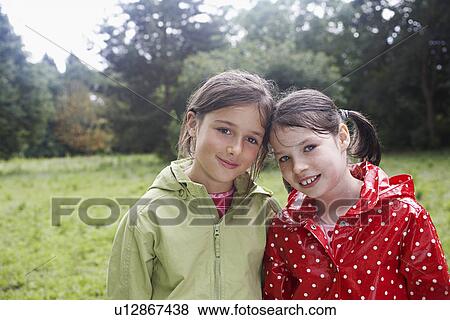 Stock Photo - Portrait of two girls (7-9) in raincoats. Fotosearch