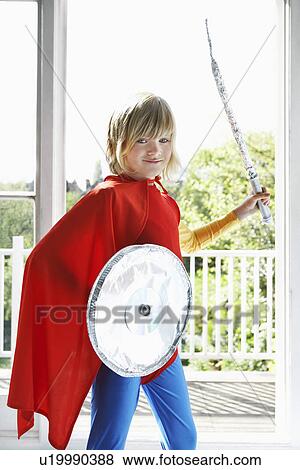 Portrait of young boy (7-9) in superhero costume holding toy shield and sword smiling View Large Photo Image Stock Photo - Portrait of young boy (7-9) in superhero costume holding toy shield and sword smiling. Fotosearch