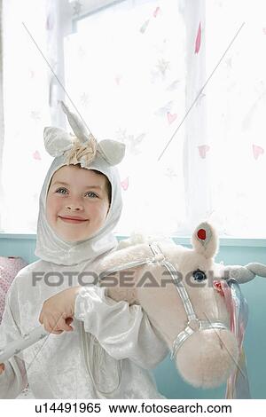 Portrait of young girl (5-6) in unicorn costume holding toy horse smiling indoors View Large Photo Image Stock Photography - Portrait of young girl (5-6) in unicorn costume holding toy horse smiling indoors. Fotosearch