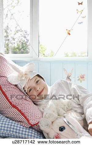 Portrait of young girl (5-6) lying on bed in unicorn costume with toy horse smiling View Large Photo Image Stock Image - Portrait of young girl (5-6) lying on bed in unicorn costume with toy horse smiling. Fotosearch