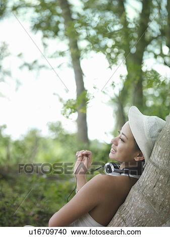 Portrait of young woman leaning on tree smiling View Large Photo Image Stock Image - Portrait of young woman leaning on tree smiling. Fotosearch