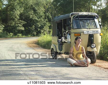 Portrait of young woman sitting cross-legged on road by moto scooter View Large Photo Image Stock Image - Portrait of young woman sitting cross-legged on road by moto scooter. Fotosearch