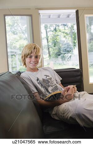 Portrait off boy (10-12) sitting on sofa with book smiling View Large Photo Image Stock Photography - Portrait off boy (10-12) sitting on sofa with book smiling. Fotosearch