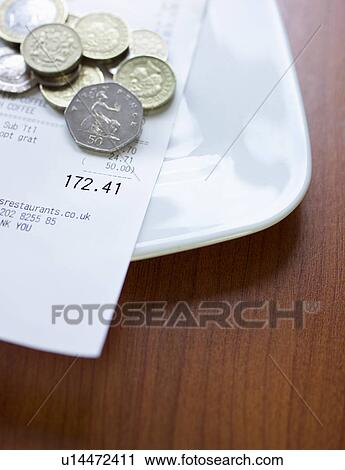 Stock Image - Pound coins and bill on plate close-up. Fotosearch