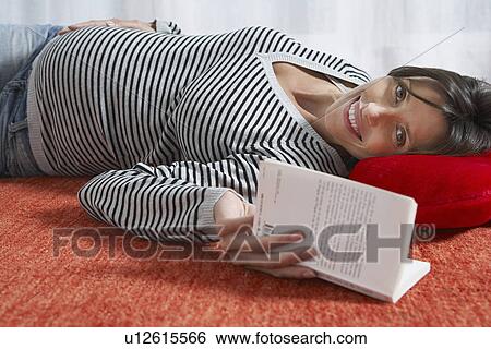 Pregnant woman lying on floor with book indoors View Large Photo Image Stock Photograph - Pregnant woman lying on floor with book indoors. Fotosearch