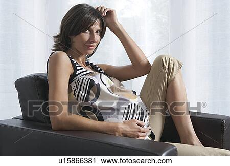 Pregnant woman sitting in armchair in living room View Large Photo Image Stock Image - Pregnant woman sitting in armchair in living room. Fotosearch