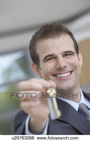 Real estate agent holding key indoors portrait View Large Photo Image Stock Photo - Real estate agent holding key indoors portrait. Fotosearch