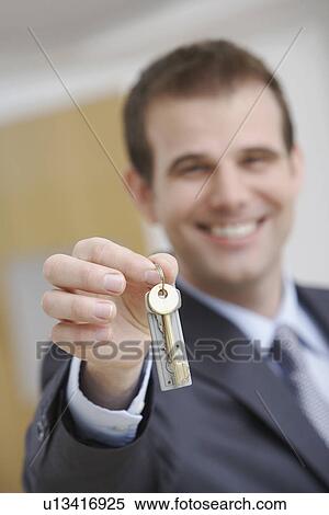 Real estate agent holding key indoors View Large Photo Image Stock Photography - Real estate agent holding key indoors. Fotosearch