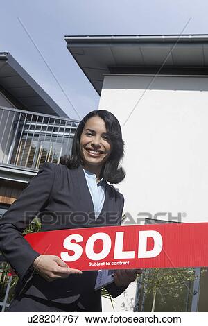 Real estate agent holding sold sign outside house portrait View Large Photo Image Stock Photo - Real estate agent holding sold sign outside house portrait. Fotosearch