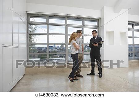 Stock Image - Real estate agent showing couple new apartment. Fotosearch