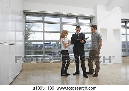 Stock Photo - Real estate agent showing couple new apartment. Fotosearch