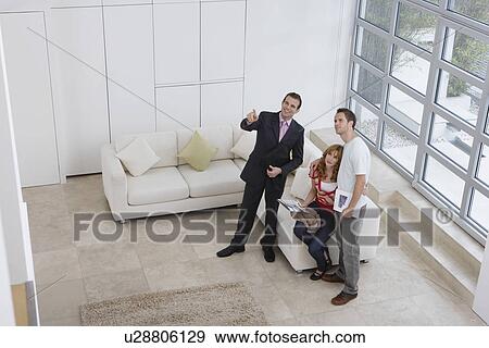 Stock Photo - Real estate agent showing couple new home elevated view. Fotosearch