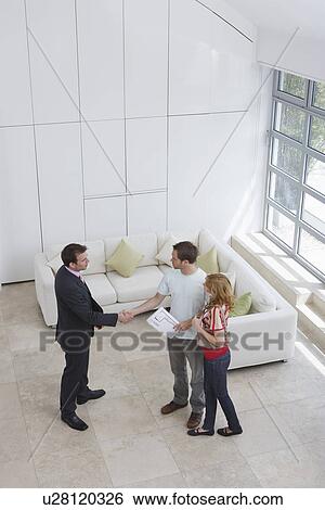 Real estate agent with couple in new home man shaking hand elevated view View Large Photo Image Stock Photograph - Real estate agent with couple in new home man shaking hand elevated view. Fotosearch