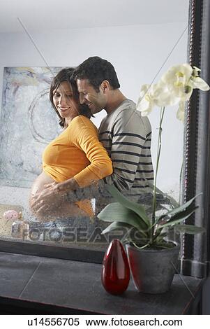 Reflection in mirror of man embracing pregnant woman from behind in bedroom View Large Photo Image Stock Photography - Reflection in mirror of man embracing pregnant woman from behind in bedroom. Fotosearch