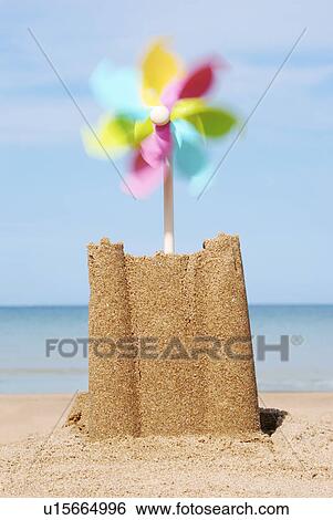 Stock Photograph - Sand castle with moving pinwheel on beach close-up. Fotosearch