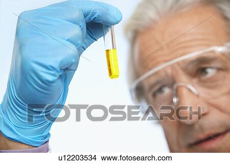 Scientist examining test tube of yellow liquid close-up focus on hand View Large Photo Image Picture - Scientist examining test tube of yellow liquid close-up focus on hand. Fotosearch