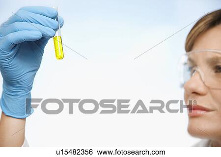 Scientist examining test tube of yellow liquid close-up focus on hand View Large Photo Image Stock Photograph - Scientist examining test tube of yellow liquid close-up focus on hand. Fotosearch