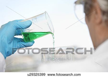 Scientist pouring green liquid in laboratory focus on hand and beaker View Large Photo Image Stock Photo - Scientist pouring green liquid in laboratory focus on hand and beaker. Fotosearch