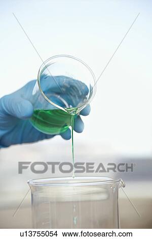 Scientist pouring green liquid into beaker close-up of hand View Large Photo Image Picture - Scientist pouring green liquid into beaker close-up of hand. Fotosearch