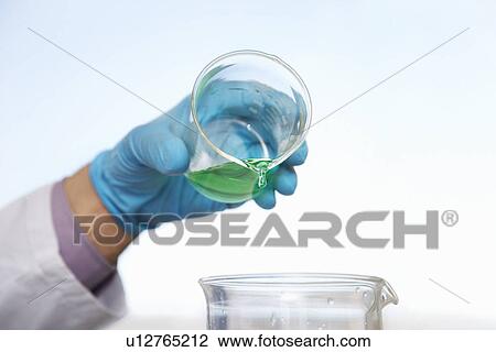 Scientist pouring green liquid into beaker close-up of hand View Large Photo Image Stock Image - Scientist pouring green liquid into beaker close-up of hand. Fotosearch