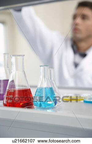 Scientist working in laboratory focus on beakers in foreground View Large Photo Image Stock Photo - Scientist working in laboratory focus on beakers in foreground. Fotosearch